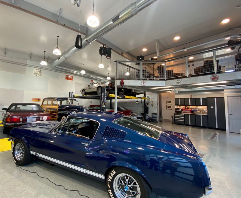 Here is an inside look into a "Newport Car Vault" private car condo garage. It includes a customized second-story mezzanine, track lighting, car lifts, and a garage mechanic center.