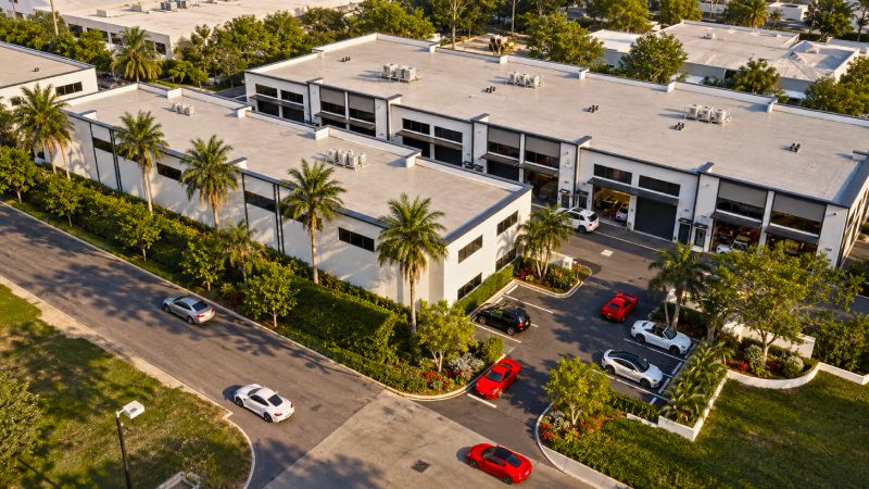 Aerial view of Jetport Motor Suites in Naples, Florida, showing the private luxury car condo community, landscaped grounds, oversized garage bays, and secure access just north of Naples Airport.